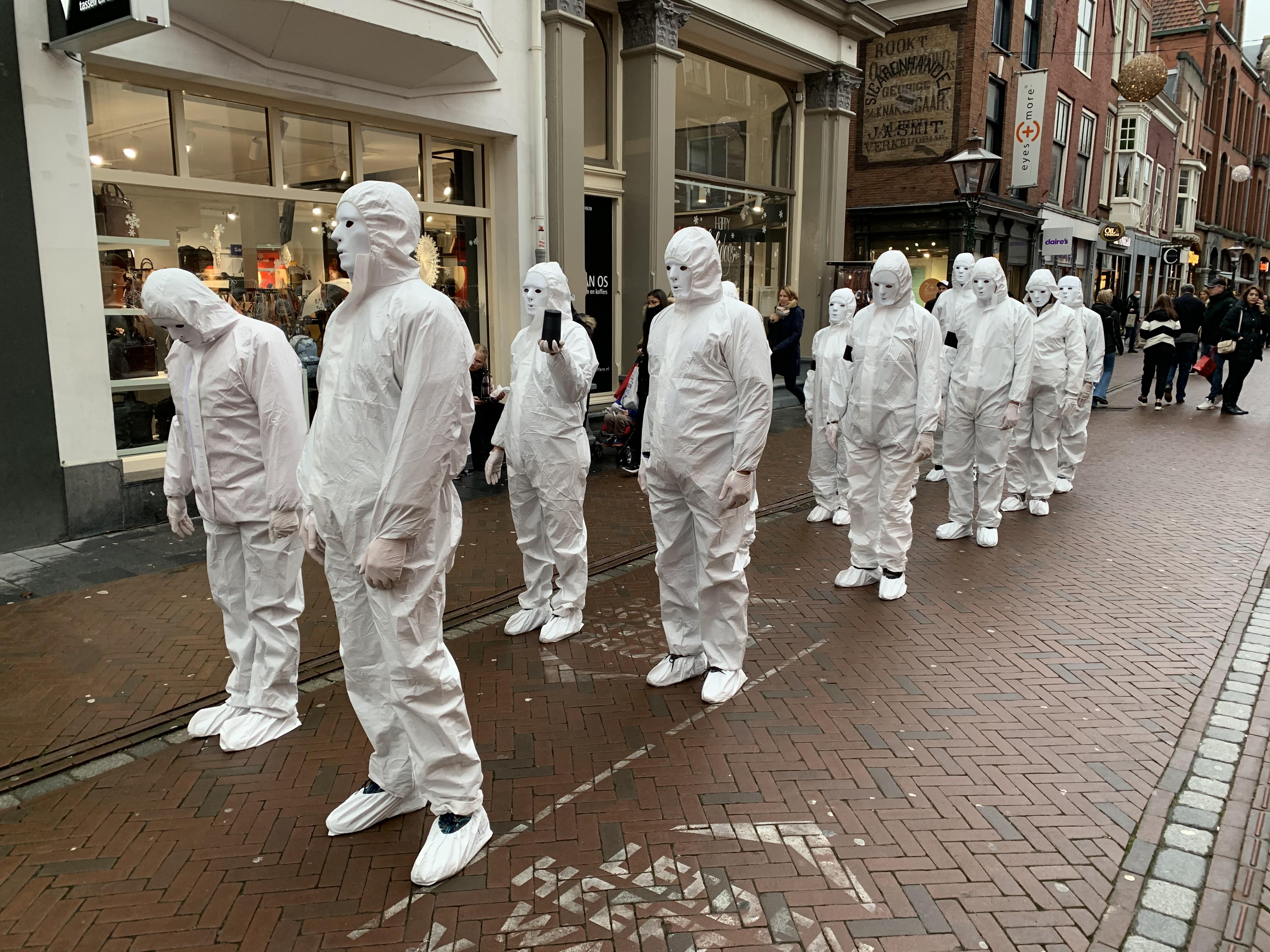 Behandeling studie element Mysterieuze groep in witte pakken, met maskers op, marcheert door drukke  Haarlemmerstraat in Leiden | Leidschdagblad